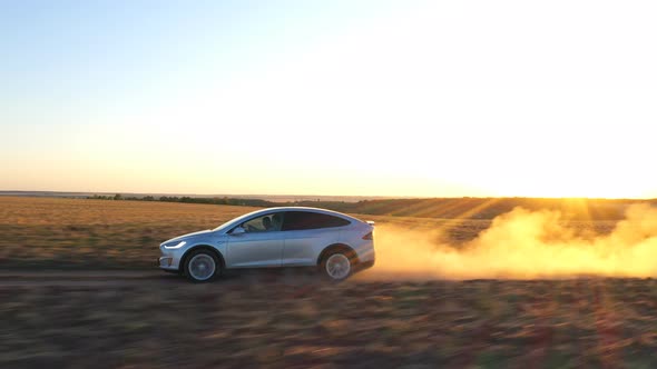 Aerial Shot of Electrical Car Speeding Through Dusty Route. Ecology Friendly Auto on Electric Charge