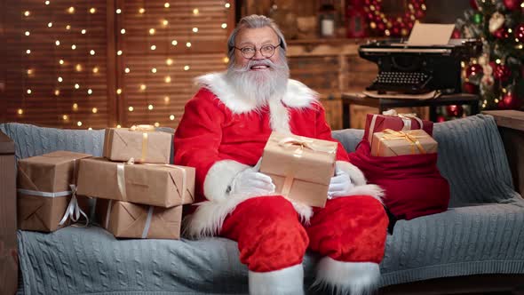 Handsome Male Santa Claus Posing with Gift Boxes at Illuminated Garland