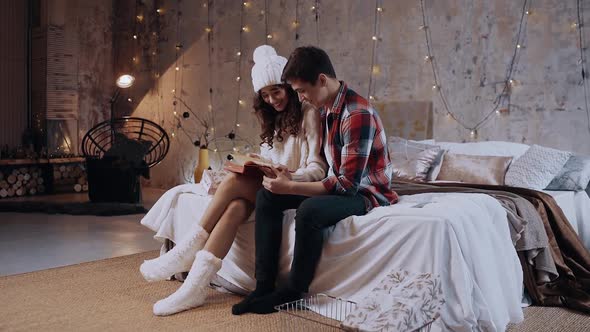 The Funny Couple Have Fun Together, Reading a Book in the Living Room Sitting on the Bed