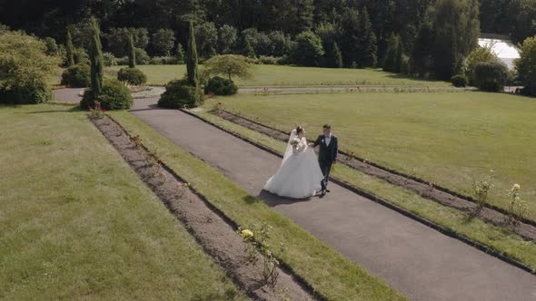 Newlyweds. Caucasian Groom with Bride Making a Kiss in Park. Wedding Couple. Man and Woman in Love