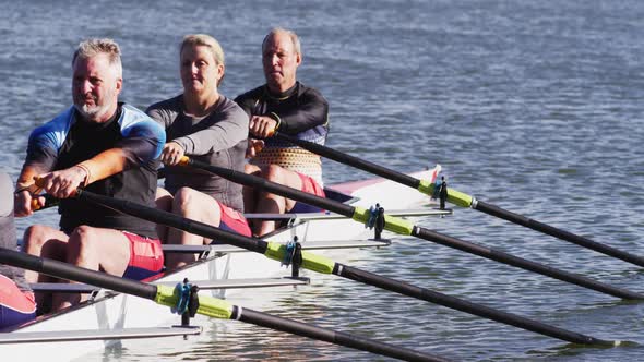 Four senior caucasian men and women rowing boat on a river