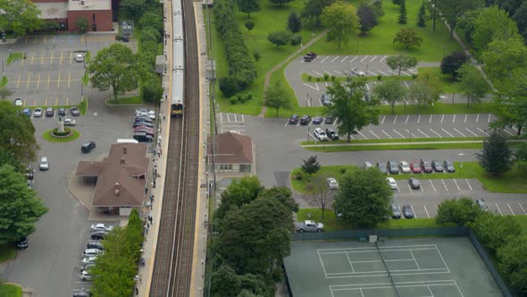 Tilt Down Aerial of Train Arriving at Station Near Tennis Courts in Long Island