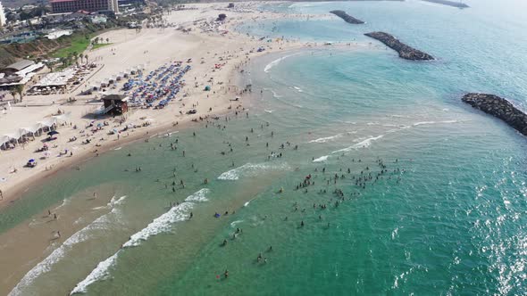 Large numbers of people enjoy the beautiful summer weather in Herzeliya Israel on the sandy beach an