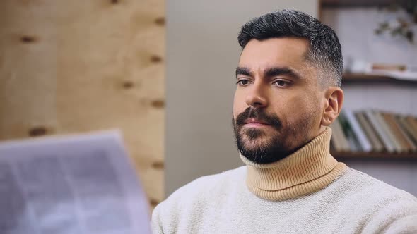 Man Browsing Through Morning News in Newspaper Looking for Something Interesting