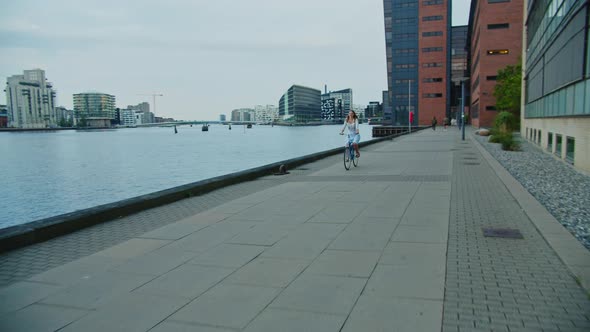 Woman Riding Bicycle Along Waterfront Promenade