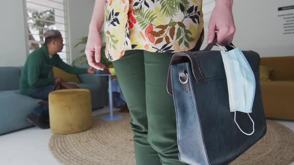 Mid section of woman with bag and face mask at office