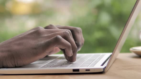 Side View of African Hands Typing on Laptop