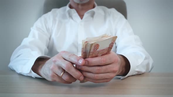 A Man Counts Out a Bundle of Five Thousand Russian Ruble Banknotes