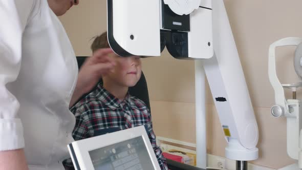 Ophthalmologist Treatment -a Woman Doctor Checking Boy's Vision Using a Big Special Device