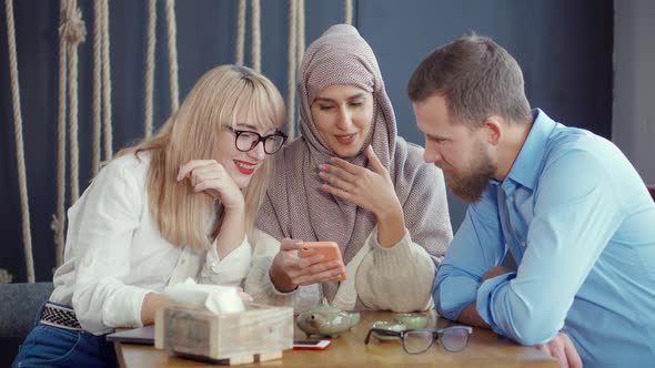 Three Multi Ethnic Friends Man and Women Are Looking in Smartphone in Cafe