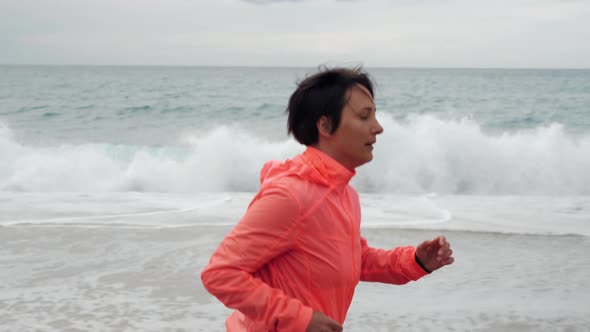 Woman is jogging on beach along sea