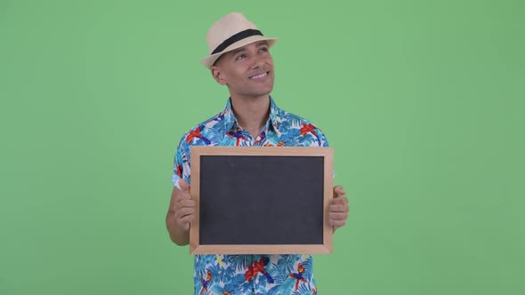 Happy Multi Ethnic Tourist Man Thinking While Holding Blackboard