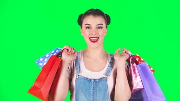 Girl with Shopping Packages of Different Colors Joyfully Dance on a Green Screen, Slow Motion