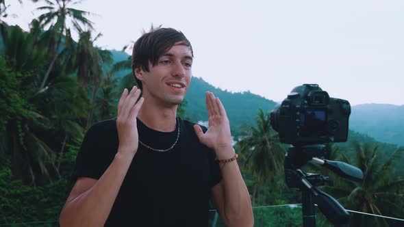 A Young Male Travel Blogger is Recording a Vlog Against the Background of Mountains in the Jungle