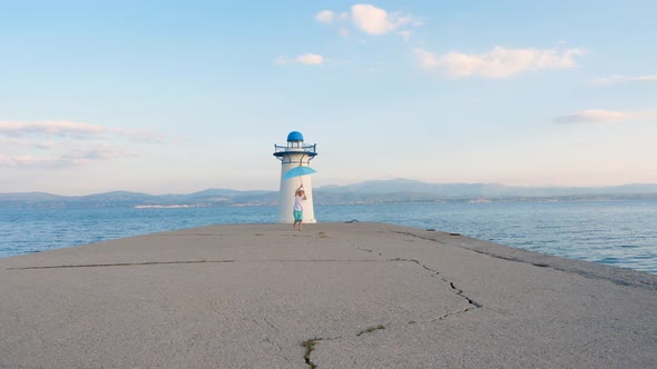 Barefoot Kid Running Along the Pier Waving His Hands Happily. Blue Umbrella in Childs Hands on Blue