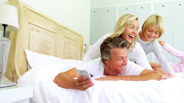 Happy family taking a selfie on mobile phone in the bed room 4k