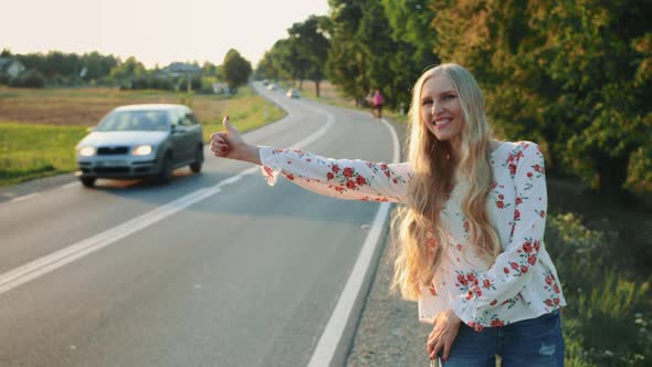 Young Woman Hitchhiking on Countryside Road. alt