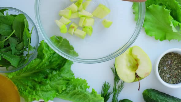 Woman Cooking Salad of Fresh Green Vegetables and Herbs