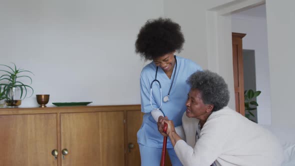 Caring african american female doctor helping senior african american female