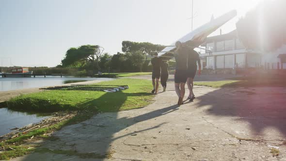 Four senior caucasian men and women carrying a rowing boat together