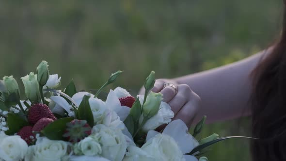 Woman's hand touches a bouquet of white roses and strawberries close-up