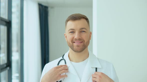 Successful Physician in White Lab Coat Looks at the Camera and Smiles in Hospital Office