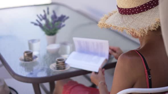 Shooting Over Shoulder of Confident Caucasian Woman Reading Turning Pages in Slow Motion Sitting at