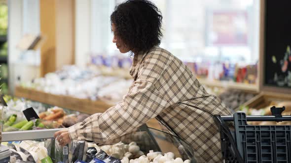 African American Stylish Woman Choosing Packed Vegetables in Supermarket