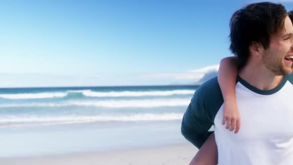 Parents giving piggyback ride to their children at beach