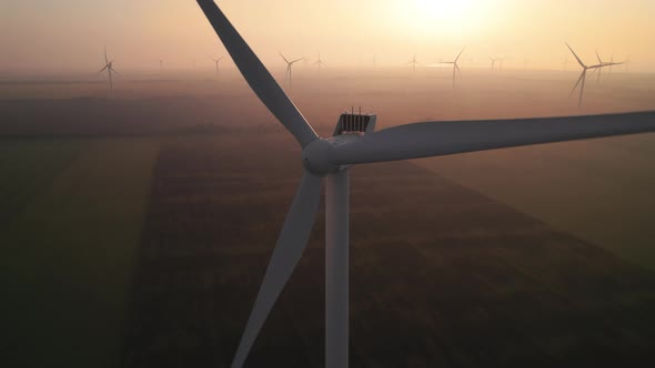 Close-up of wind turbine blades at sunset or sunrise.