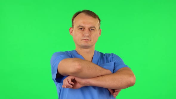 Medical Man Folds His Arms Over His Chest and Looks Seriously at the Camera. Green Screen
