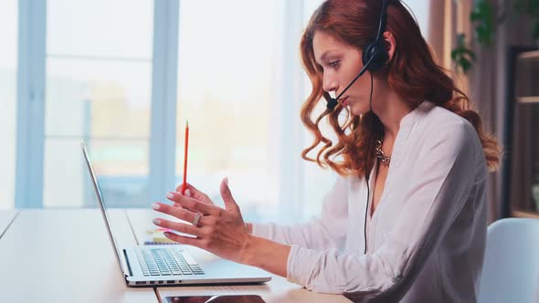 Professional Caucasian Woman Call Center Employee Looks at Laptop Sits at Table