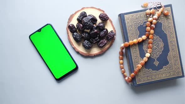 Smart Phone Holy Book Quran and Rosary on Table