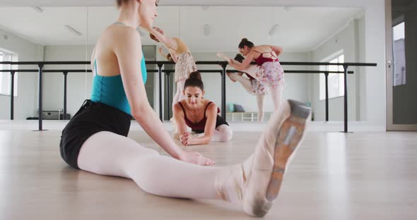 Caucasian ballet female dancers stretching up with a barre before a ballet class