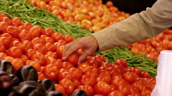 Man selecting tomatoes in organic section