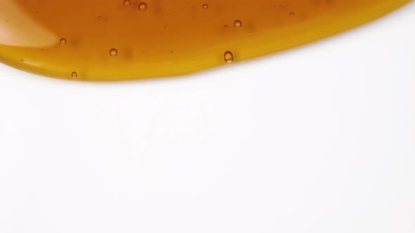 Thick honey flows down a white background. Abstract colorful background with small bubbles