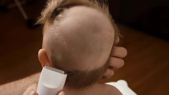 Father Shaving a Little Boy's Head with Electric Hair Clipper