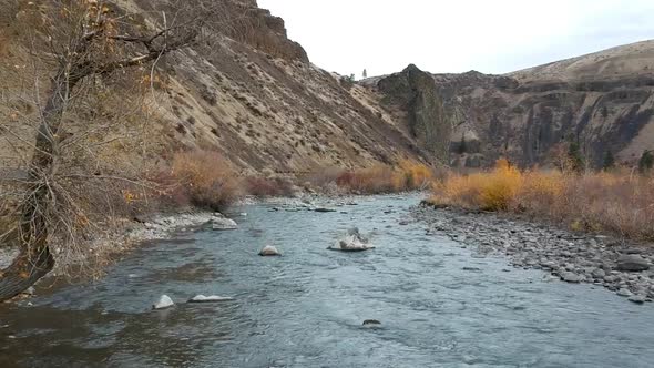 Ariel drone footage of a rugged river valley in fall.