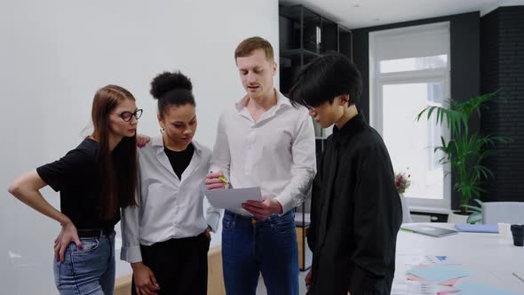 A Male Leader Shows Plans on Paper to His Multicultural Team