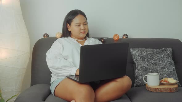 Asian Plus Size Woman Working Online with Laptop at Home