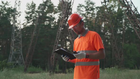 A Workman in the Electrical Station Walking and Reporting By Radio Verifying Information in a