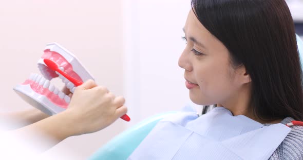 Dentist teaching patient how to brush teeth