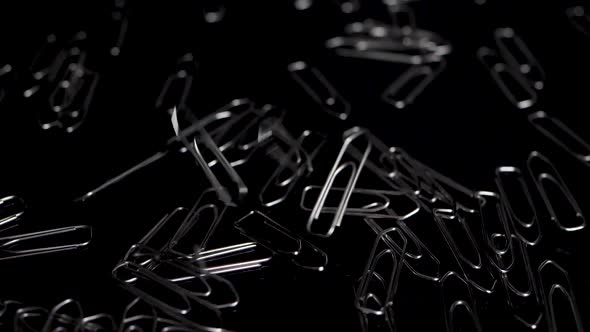 Macro slide shot over paper clips, more paper clips falling down in slow motion.