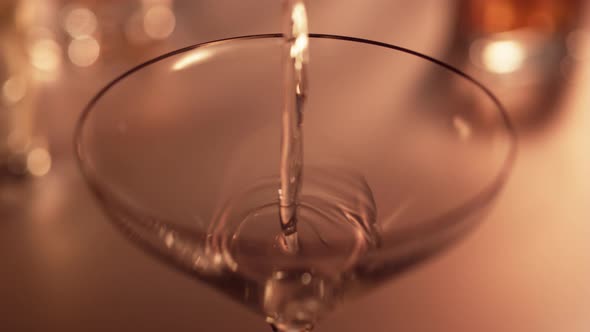 Pouring martini into empty glass. Slow Motion.