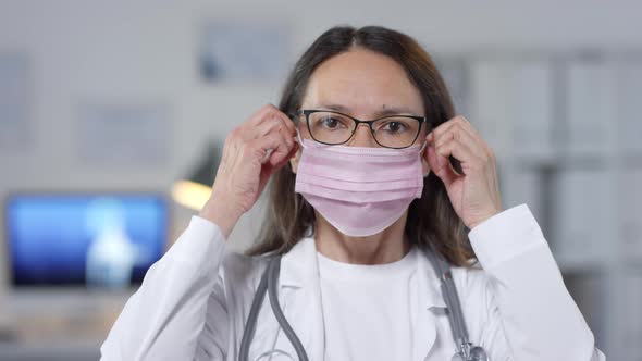 Mature Doctor Taking Off Mask