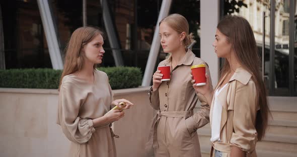 Attractive Female Friends Holding Paper Coffee Cups and Smiling at Street, Young Women Having