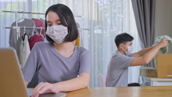 Asian young couple wear mask and sell product online live streaming during covid pandemic from home.