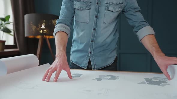 Close Up Shot of Young Man Hands Engineer Opening the Paper and Checking the Construction Drawings