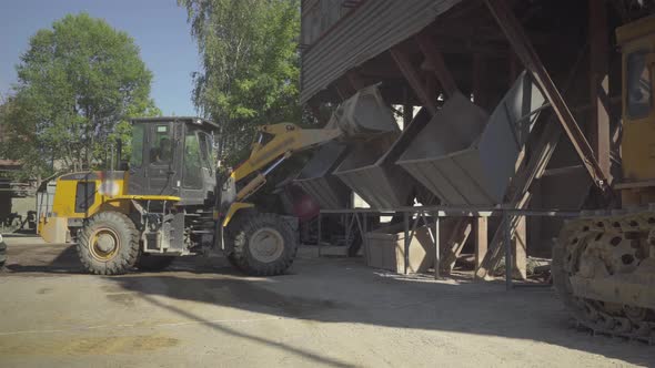 Wide Shot of Tractor Unloading Bulk Material on Production Site on Sunny Day. Machinery Working on