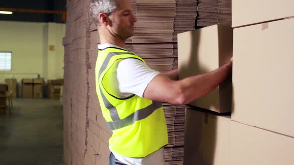 Warehouse worker stacking cardboard boxes